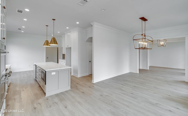 kitchen featuring light hardwood / wood-style floors, hanging light fixtures, a center island, a notable chandelier, and white cabinets