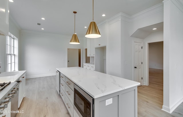 kitchen with pendant lighting, a kitchen island, white cabinetry, appliances with stainless steel finishes, and sink