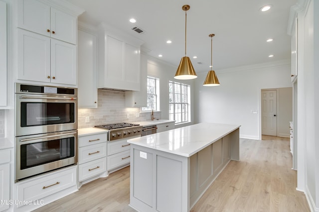 kitchen featuring white cabinetry, pendant lighting, a center island, and appliances with stainless steel finishes