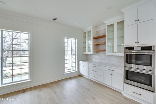 kitchen with light hardwood / wood-style flooring, a wealth of natural light, backsplash, white cabinetry, and double oven