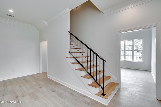 stairway with ornamental molding and hardwood / wood-style flooring