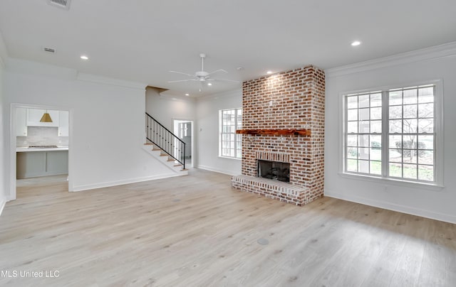 unfurnished living room featuring a brick fireplace, plenty of natural light, and crown molding