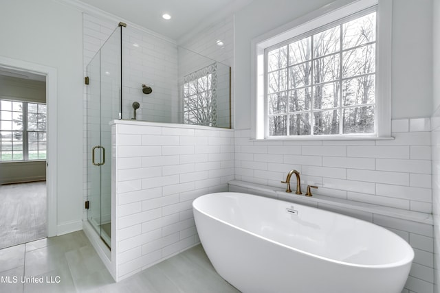 bathroom featuring shower with separate bathtub, tile walls, and ornamental molding