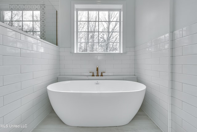 bathroom featuring tile walls, a tub to relax in, and plenty of natural light