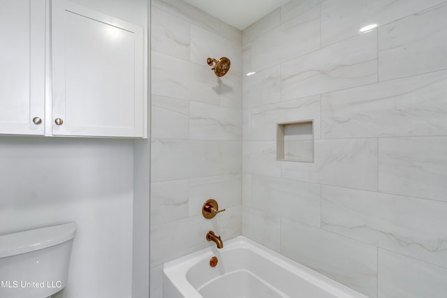 bathroom featuring toilet and tiled shower / bath