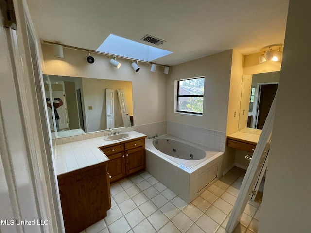 bathroom featuring vanity, tiled bath, a skylight, and tile patterned flooring