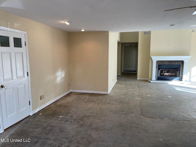 unfurnished living room featuring a tile fireplace and ceiling fan