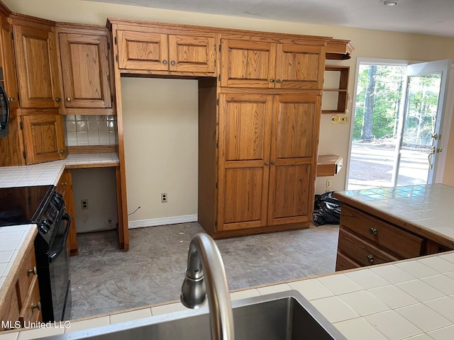 kitchen with sink, black appliances, tile counters, and backsplash