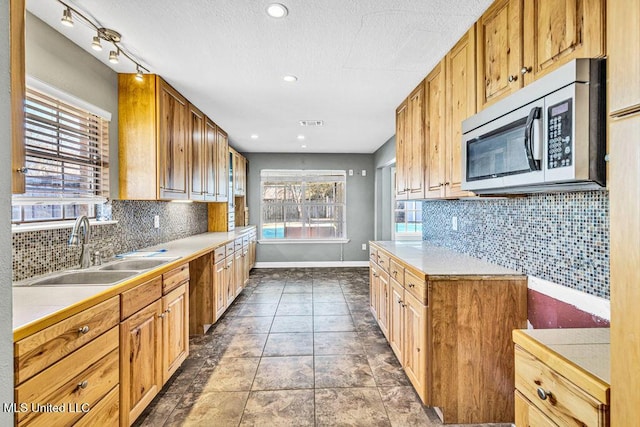 kitchen with tasteful backsplash, sink, a textured ceiling, and dark tile patterned floors