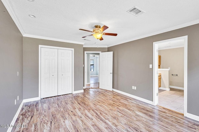 unfurnished bedroom featuring light hardwood / wood-style flooring, ceiling fan, crown molding, a textured ceiling, and a closet