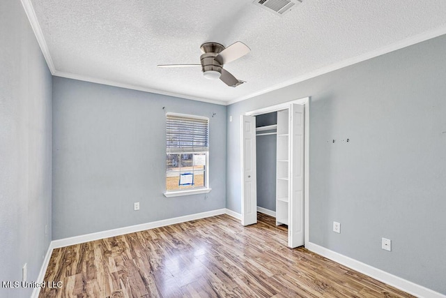 unfurnished bedroom featuring crown molding, ceiling fan, a closet, and light wood-type flooring