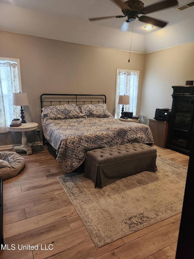 bedroom featuring ceiling fan, visible vents, and wood finished floors