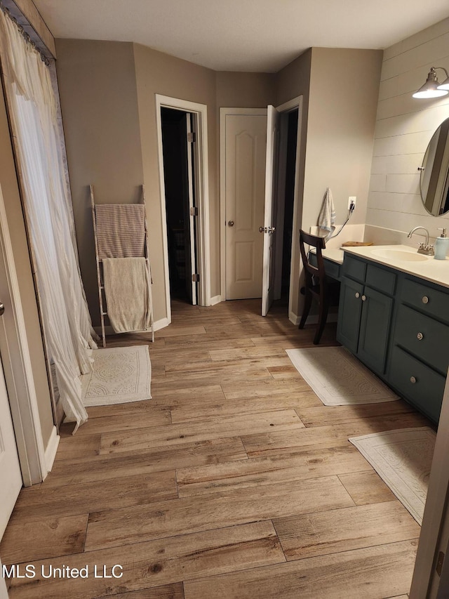 bathroom featuring baseboards, wood finished floors, and vanity