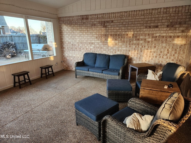 living area featuring lofted ceiling and brick wall