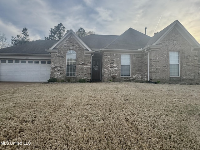 ranch-style house with a front yard, an attached garage, brick siding, and concrete driveway