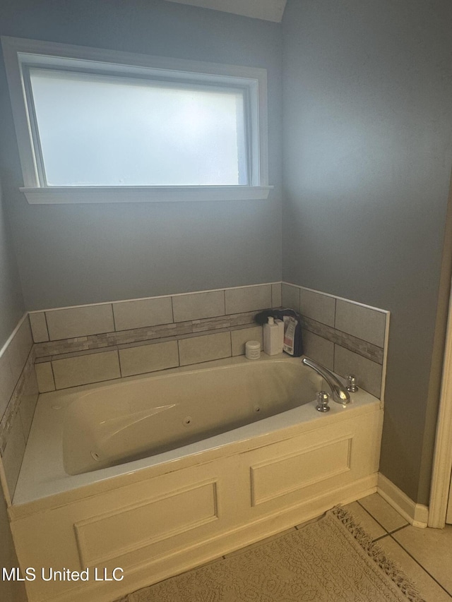 bathroom featuring a tub with jets, a wealth of natural light, and tile patterned flooring