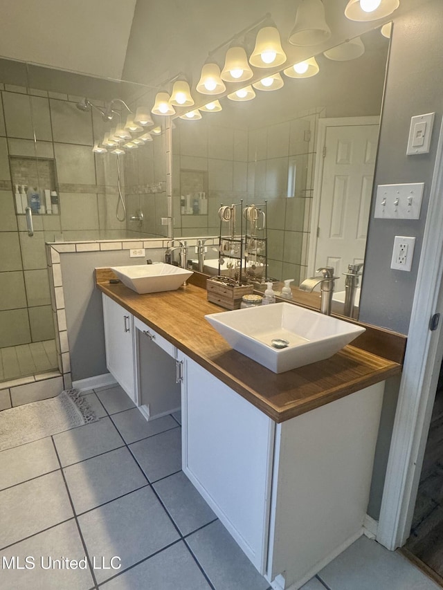full bathroom with a stall shower, double vanity, tile patterned flooring, and a sink
