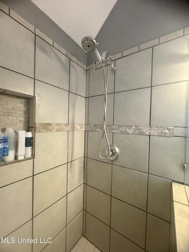 bathroom with a textured ceiling and a tile shower