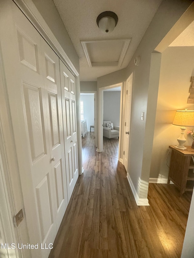 hall featuring attic access, dark wood-style floors, and baseboards