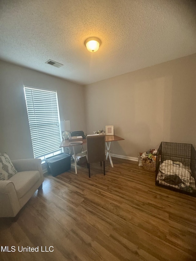 playroom featuring baseboards, a textured ceiling, visible vents, and wood finished floors