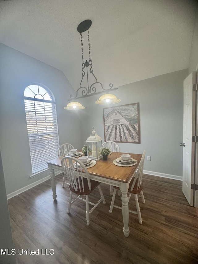 dining area featuring dark wood-style flooring, baseboards, vaulted ceiling, and a textured ceiling