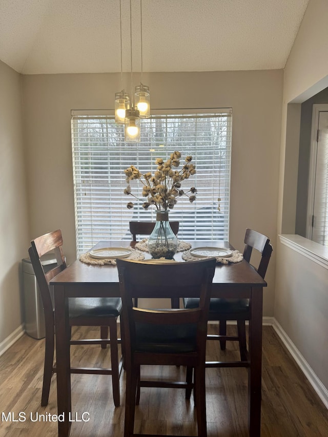 dining area with a textured ceiling, baseboards, wood finished floors, an inviting chandelier, and vaulted ceiling
