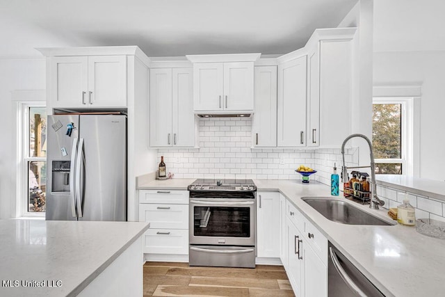 kitchen featuring tasteful backsplash, sink, stainless steel appliances, and white cabinets