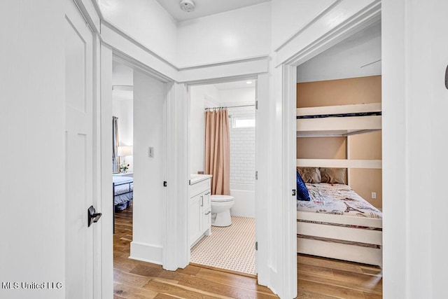 interior space featuring hardwood / wood-style flooring, vanity, toilet, and shower / bath combo with shower curtain