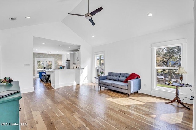 living room with high vaulted ceiling, light hardwood / wood-style floors, and a wealth of natural light