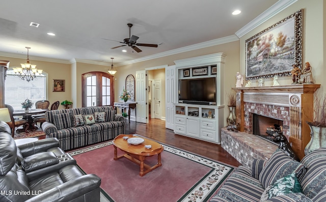 living room featuring french doors, a brick fireplace, dark hardwood / wood-style floors, ceiling fan with notable chandelier, and ornamental molding