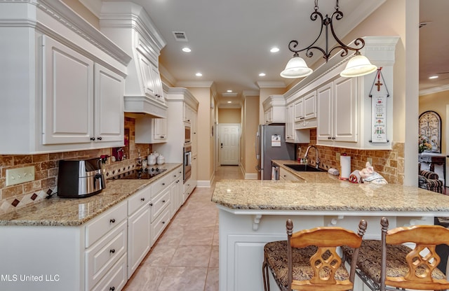 kitchen featuring stainless steel appliances, a kitchen breakfast bar, kitchen peninsula, decorative light fixtures, and white cabinets