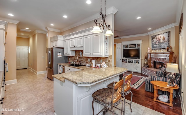 kitchen featuring pendant lighting, a breakfast bar, white cabinets, sink, and kitchen peninsula