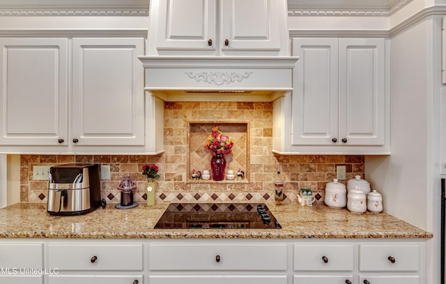 kitchen featuring black electric cooktop, decorative backsplash, white cabinets, and light stone counters