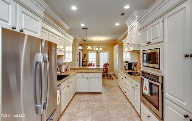 kitchen featuring stainless steel appliances, kitchen peninsula, a chandelier, pendant lighting, and white cabinets