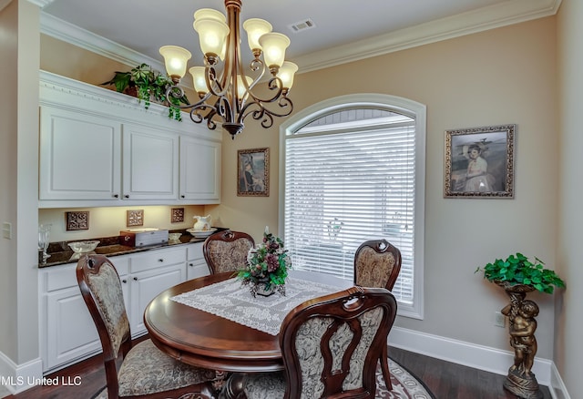 dining room with dark hardwood / wood-style flooring, ornamental molding, and a chandelier