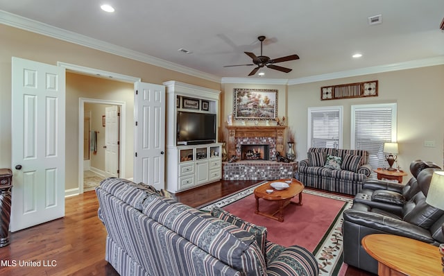 living room featuring ceiling fan, dark hardwood / wood-style flooring, crown molding, and a brick fireplace