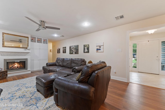 7829 Alawai Ave, Diamondhead, MS 39525 - living room featuring wood finished floors, ceiling fan, a glass covered fireplace, and visible vents