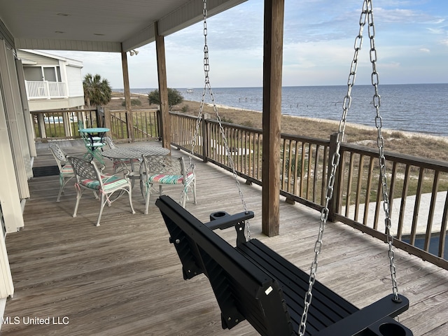 wooden deck featuring a water view and a view of the beach