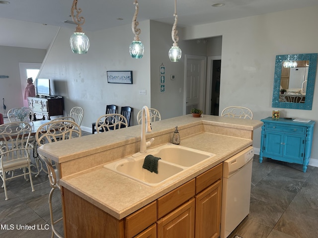 kitchen featuring a center island with sink, dishwasher, light countertops, pendant lighting, and a sink