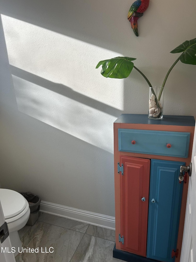 interior details featuring toilet and baseboards