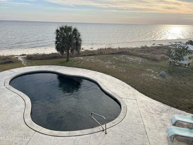 pool at dusk featuring a water view