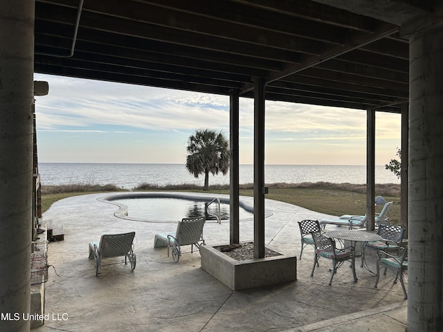 patio terrace at dusk featuring a water view