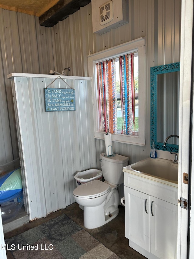 bathroom featuring vanity, toilet, and wooden walls