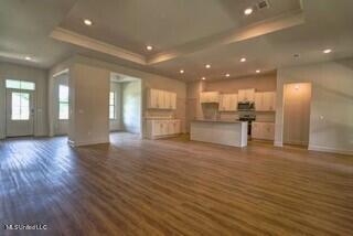 unfurnished living room with dark wood-type flooring and a tray ceiling