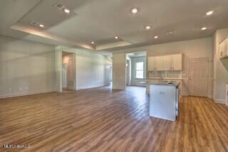 kitchen featuring dark wood-type flooring, a raised ceiling, and a kitchen island