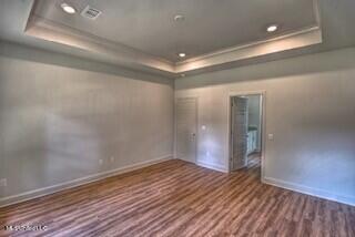 empty room with dark hardwood / wood-style flooring and a raised ceiling