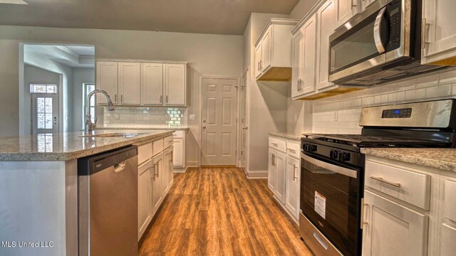 kitchen with appliances with stainless steel finishes, white cabinetry, hardwood / wood-style flooring, and sink