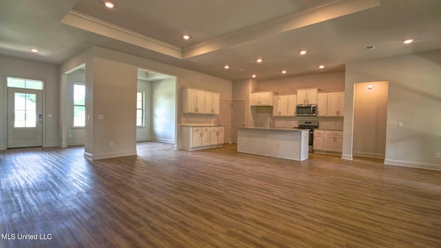 unfurnished living room featuring crown molding, a tray ceiling, and dark wood-type flooring