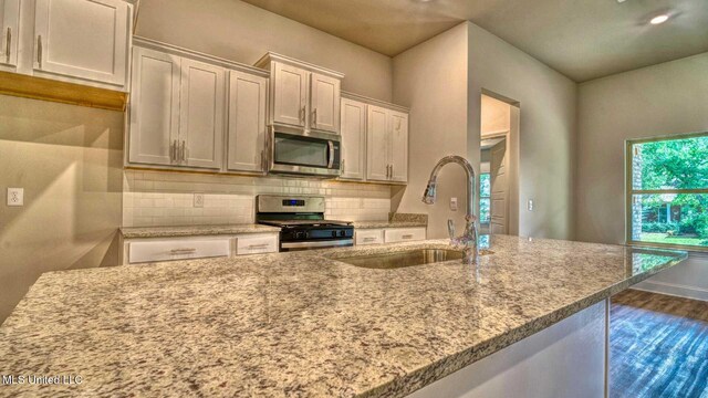 kitchen featuring sink, backsplash, stainless steel appliances, white cabinets, and dark wood-type flooring