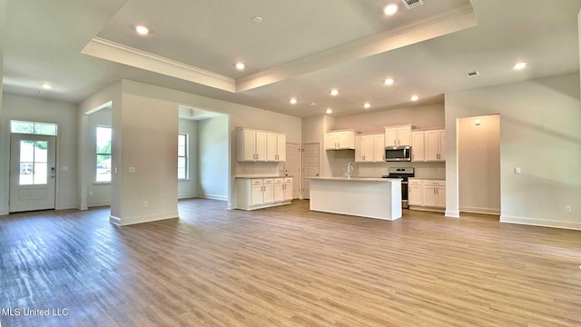 unfurnished living room with light wood-type flooring and a raised ceiling